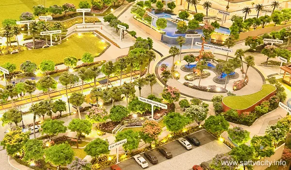 A close-up of a miniature real estate model showing labeled zones such as 'Youth Gathering Nook,' 'Car Parking,' and 'Green Theater.' The layout includes winding paths, dense miniature shrubbery, and a circular roundabout with a feature sculpture.