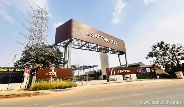 View of the grand entrance arch and main gate of Sattva City project featuring modern branding and landscape design.