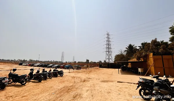 A ground-level view of the Sattva City construction site showing a dirt access road, construction materials, and a Parcel sign indicating land divisions under a bright sky.